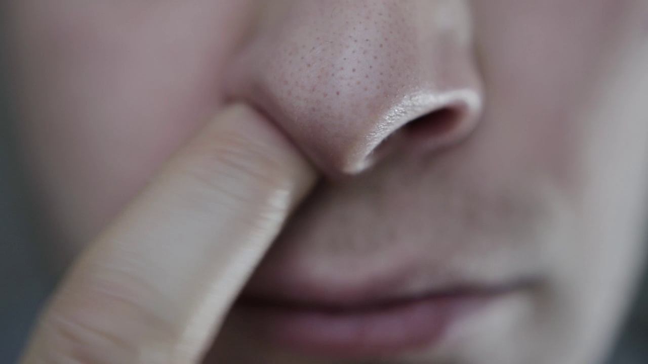 一个男人从鼻孔里取出鼻涕。人类疾病鼻热病，特写镜头视频下载