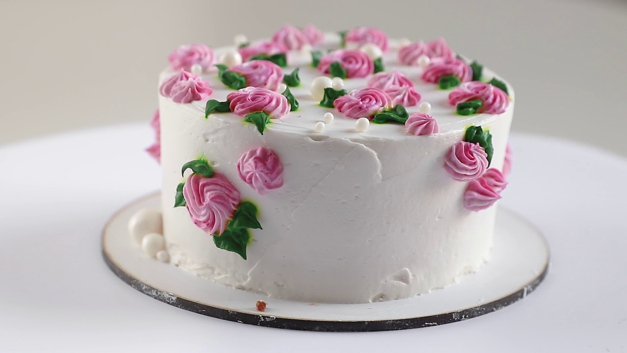 蛋糕与白色奶油和粉红色玫瑰旋转特写，侧视图视频下载