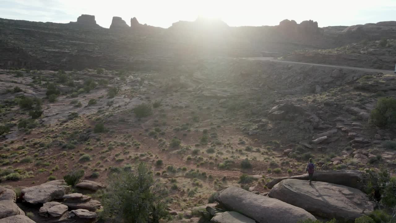 无人机漂亮的运动年轻女子徒步在广阔的沙漠景观摩押在犹他州西南部的沙漠视频素材