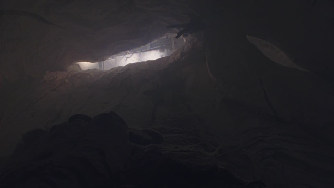 洞穴内部的上角。看到登山者悬挂在洞穴的天花板上。看到大块的雪和冰从洞顶的裂缝中落下。看到爬山的人往坡上跌倒。看到绳子从攀登者连接到天花板和连续的冰雪视频下载