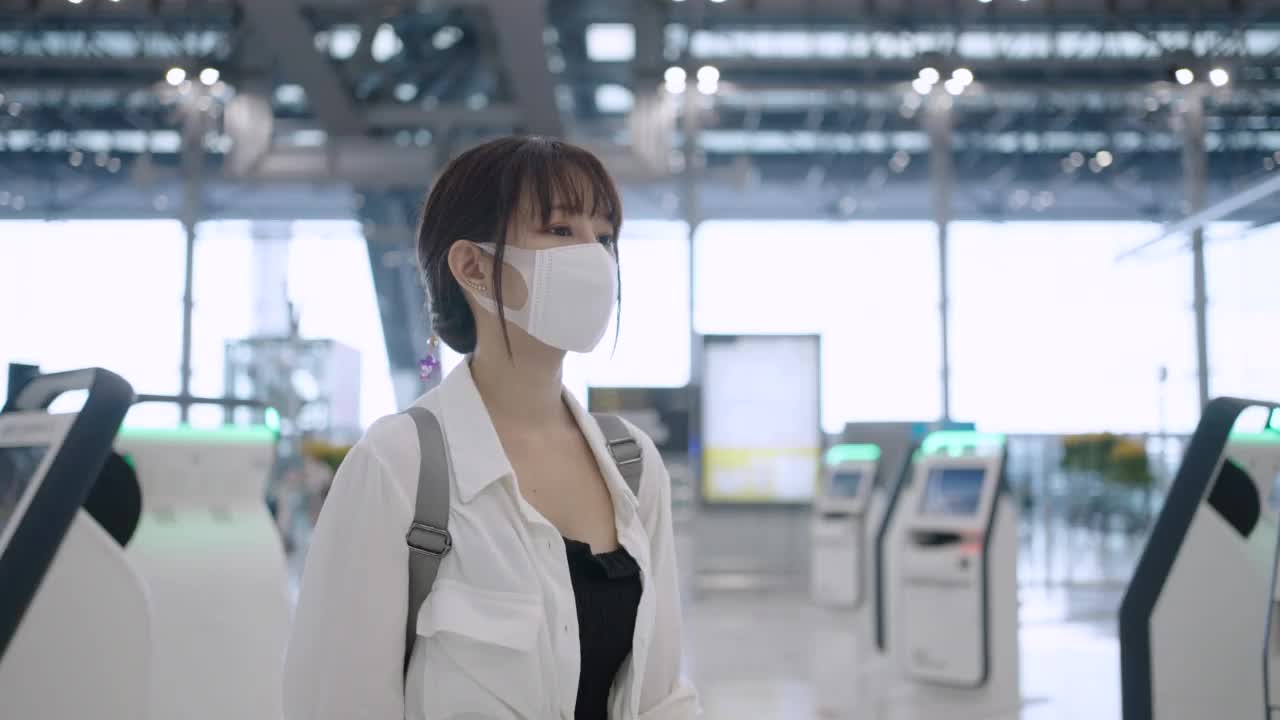 戴着口罩的亚洲年轻女子在机场候机楼自助登机视频素材