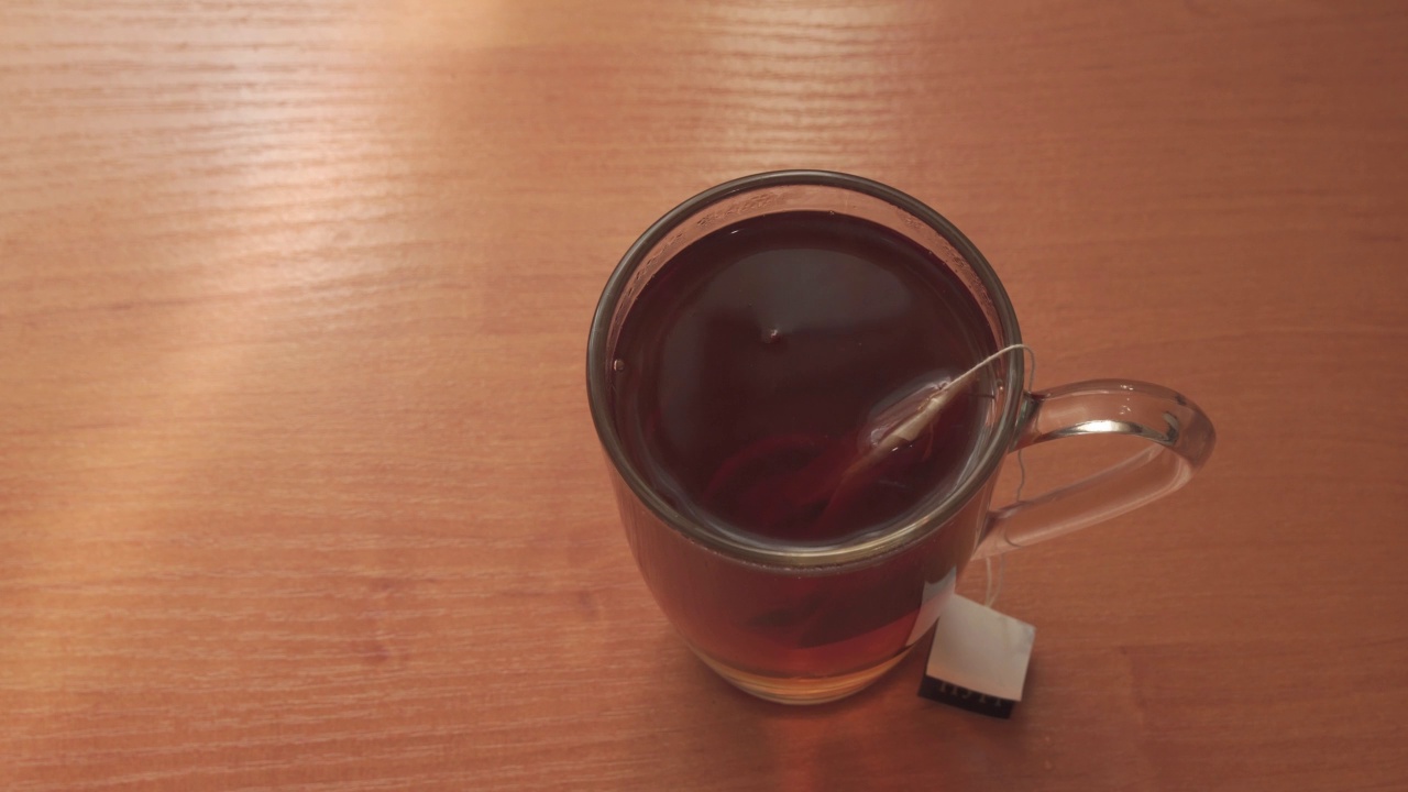 把热水倒进杯子里泡茶。把茶包浸入沸水中。视频素材