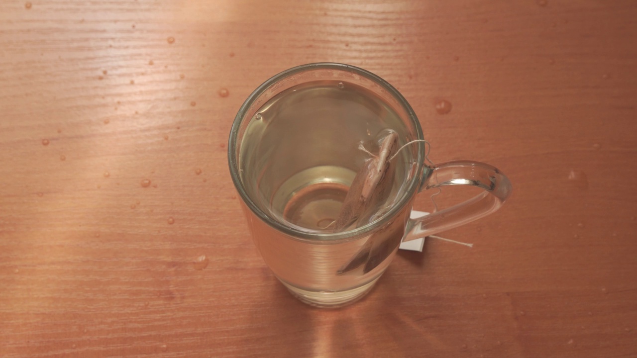 把热水倒进杯子里泡茶。把茶包浸入沸水中。视频素材