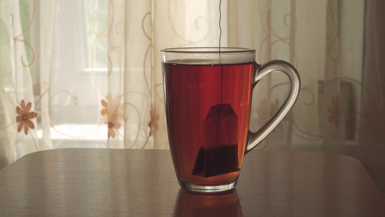 将茶包浸在沸水中，沸水倒入玻璃杯中。热饮:热饮的配制将茶包浸在沸水中，沸水倒入玻璃杯中。热饮:热饮的配制视频素材
