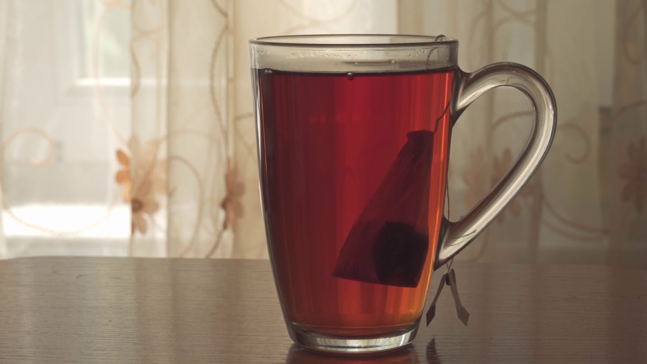 将茶包浸在沸水中，沸水倒入玻璃杯中。热饮:热饮的配制将茶包浸在沸水中，沸水倒入玻璃杯中。热饮:热饮的配制视频素材
