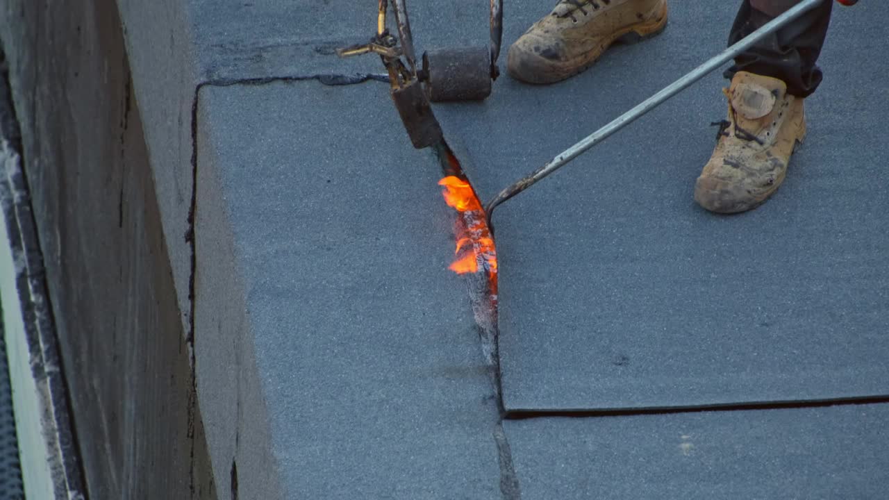 承包商工人铺设屋顶油毡使用丙烷气燃烧器火炬焊接沥青板视频下载
