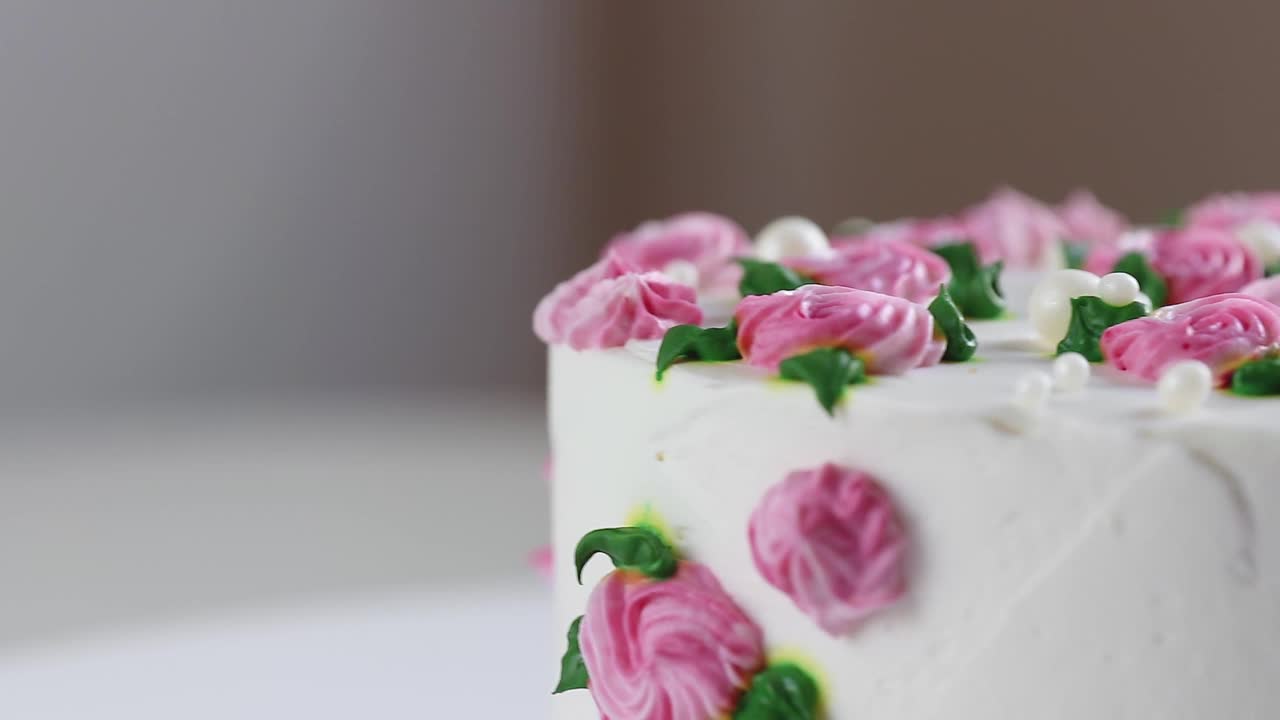 蛋糕与白色奶油和粉红色玫瑰旋转特写。摄像机的平移运动视频下载