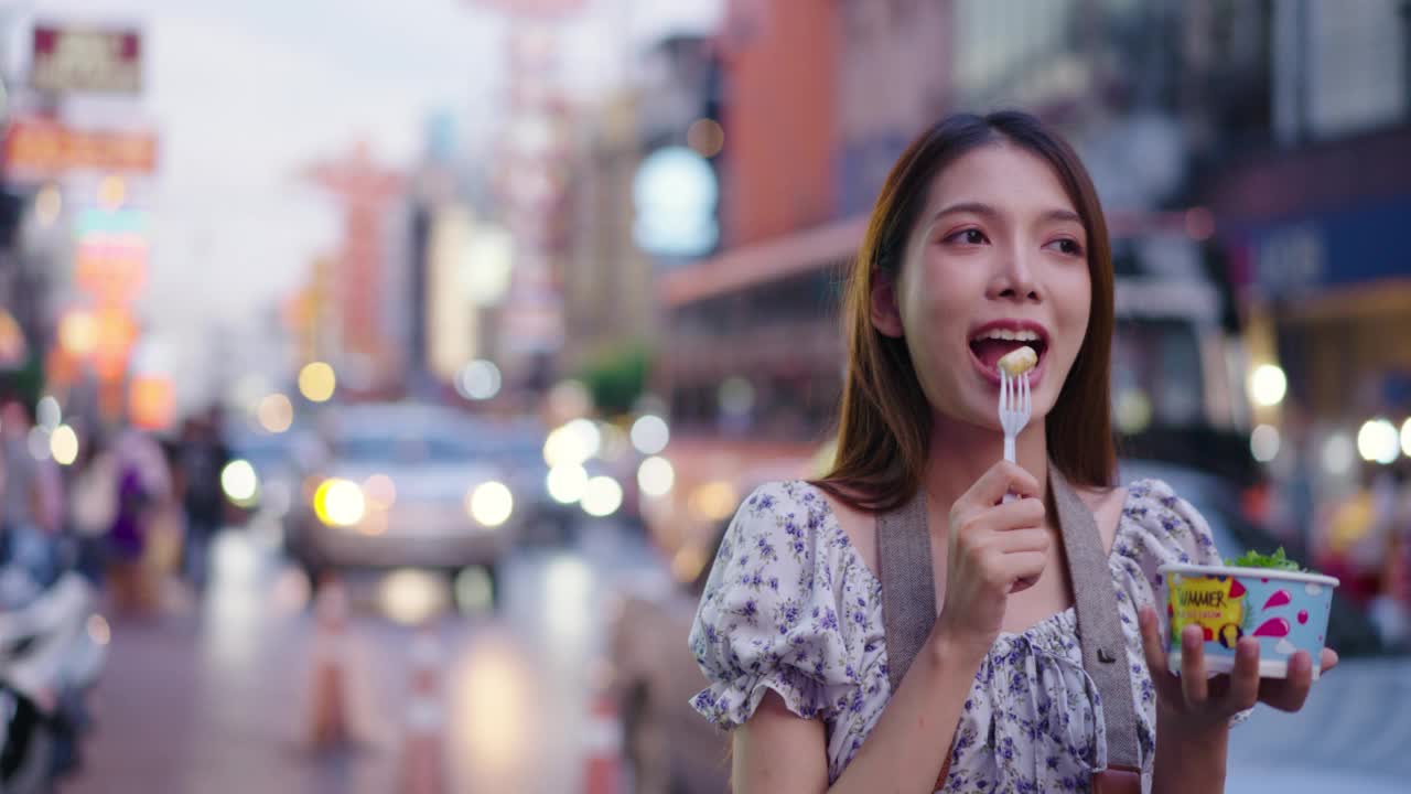 女游客在街头小吃街吃冰淇淋。视频素材