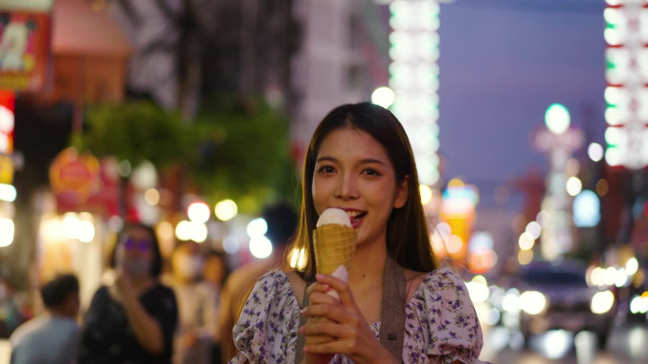女游客在街头小吃街吃冰淇淋。视频下载