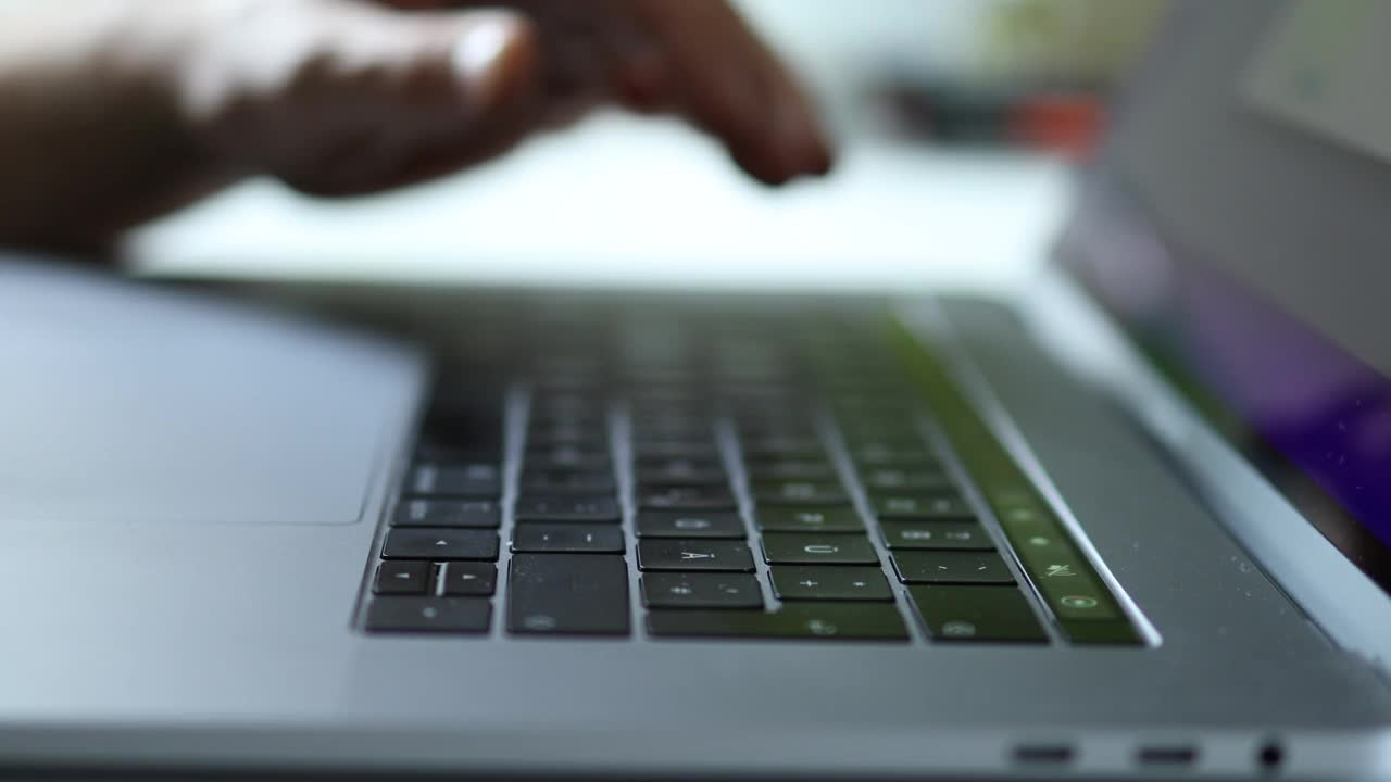 一个男人戴着婚戒的手在笔记本电脑上工作的特写视频素材