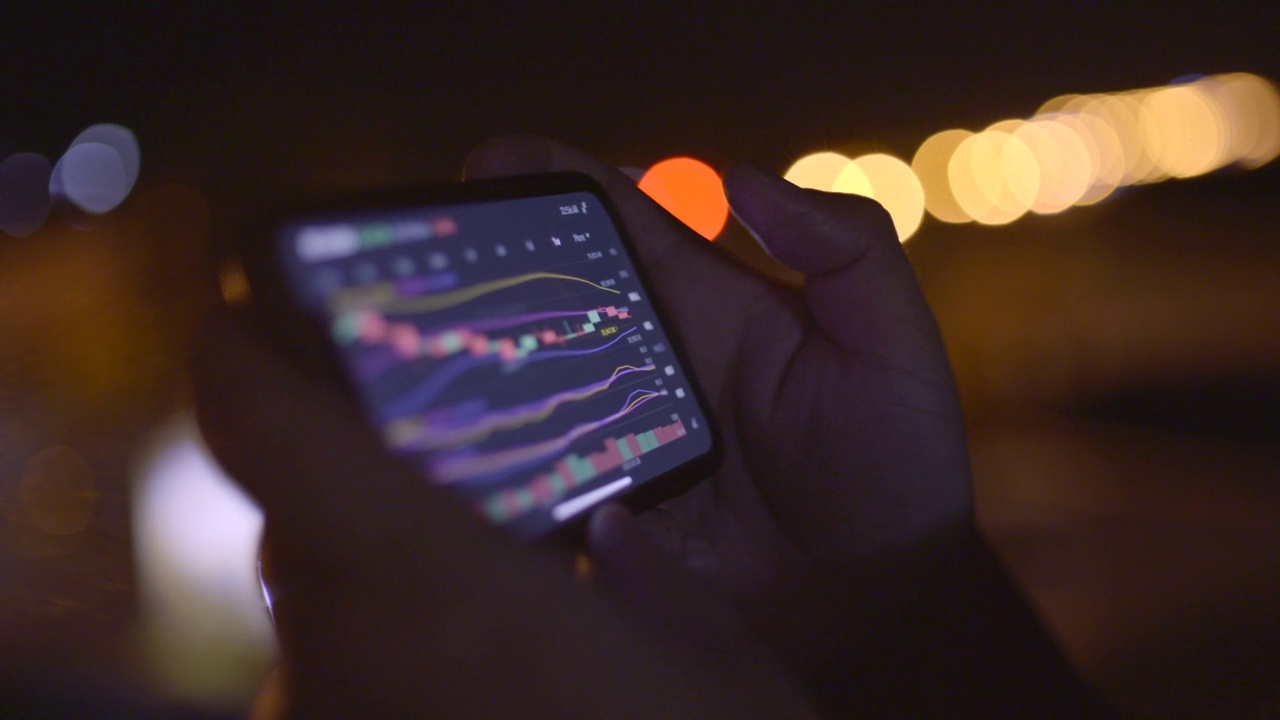 夜间用散光背景在手机上检查股票市场或加密货币数据视频素材