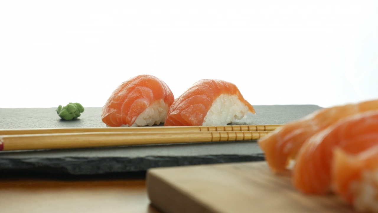 三文鱼生鱼片寿司和芥末酱板和木制砧板上的筷子视频下载