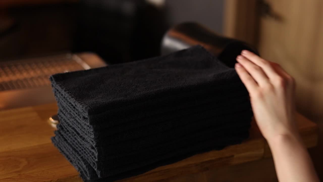 一名家庭主妇用手触摸一叠刚洗干净的亚麻布。黑色的毛巾。家庭作业。在洗衣店洗衣服。高质量的全高清镜头。视频下载