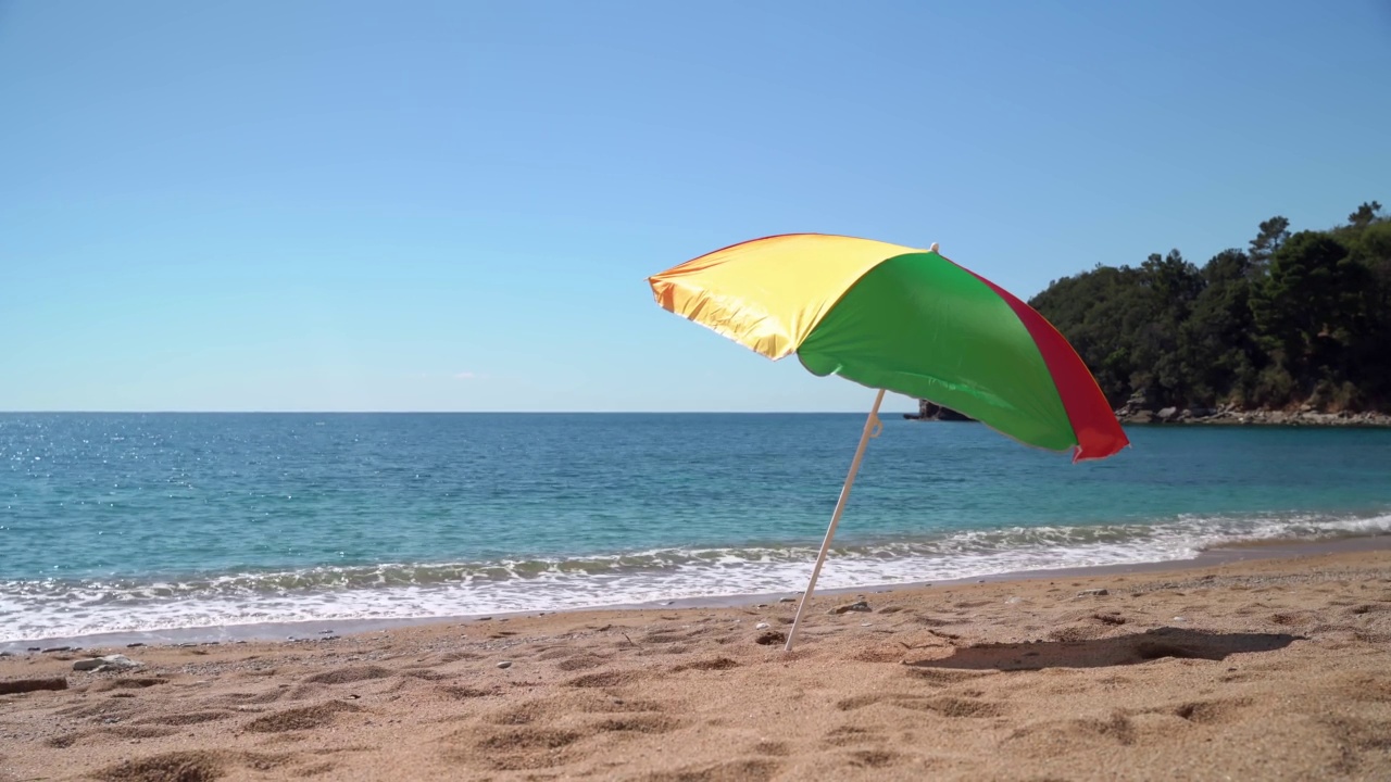 海滩上有明亮的遮阳伞，背景是明亮的蓝色天空和海浪。旅游的天堂视频素材
