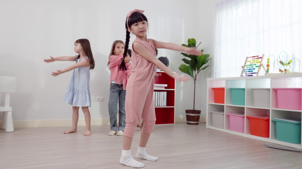 6岁的亚洲小女生，穿着粉红色的休闲服装，微笑可爱，是课堂上的现代舞学生组的领舞。视频素材