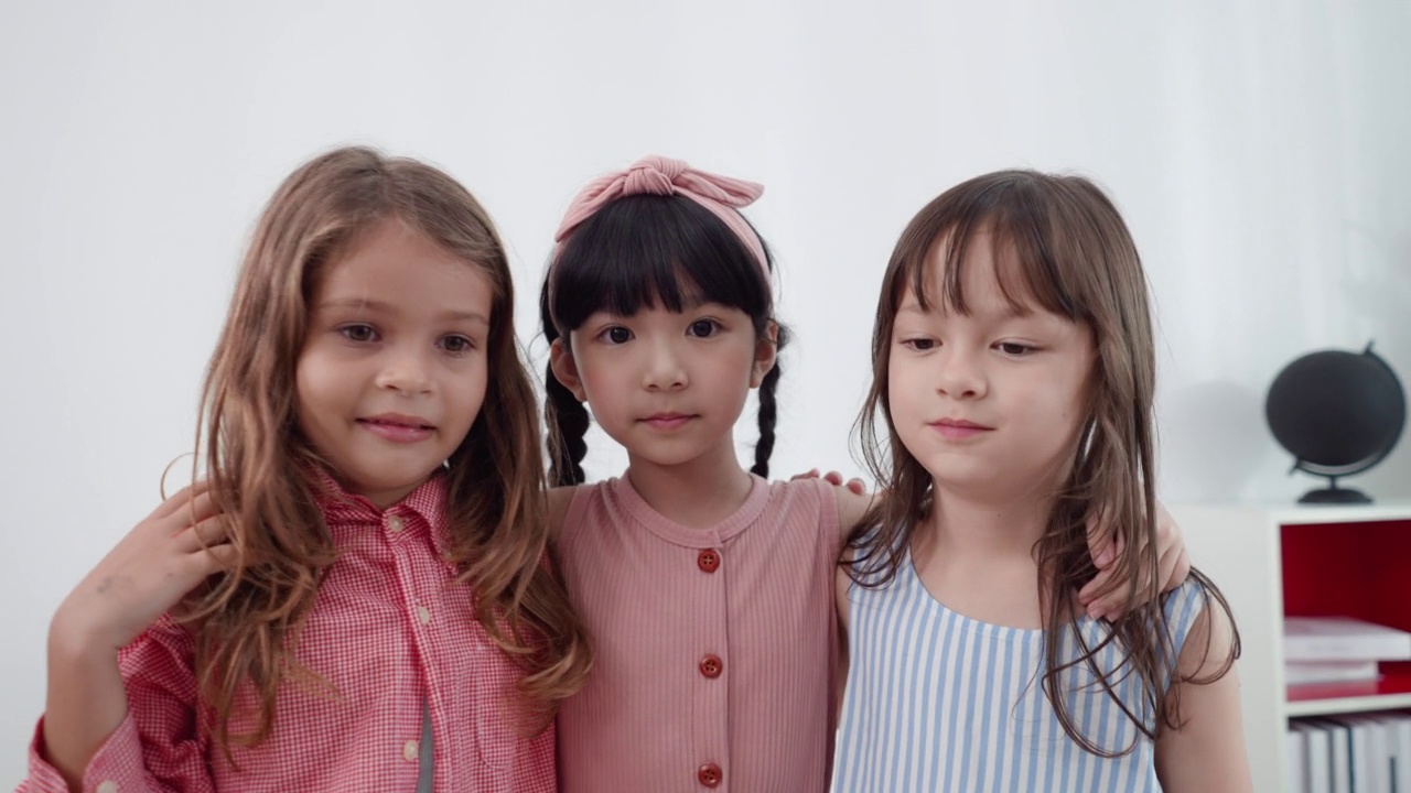 3名可爱的亚洲小学女生站在教室前，双手环抱，脸上洋溢着笑容。回到学校。视频素材