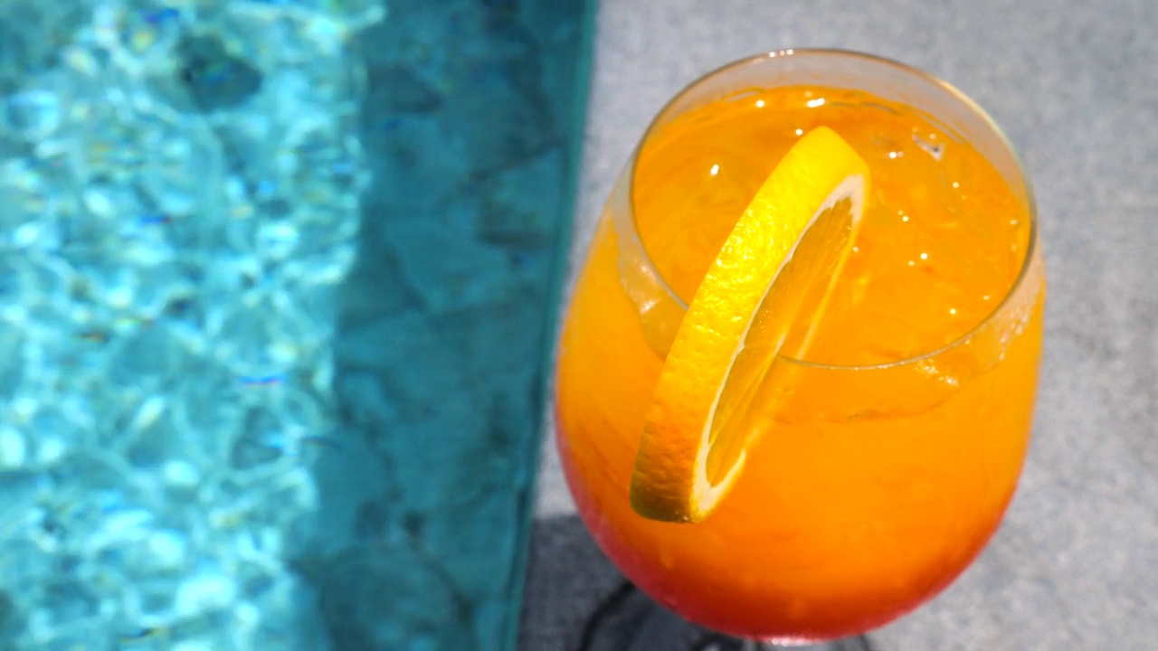 橙色点心鸡尾酒饮料在池边的特写。暑假视频素材