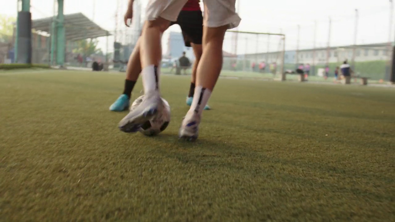 一名亚洲运动员和他的朋友在户外踢足球。视频下载