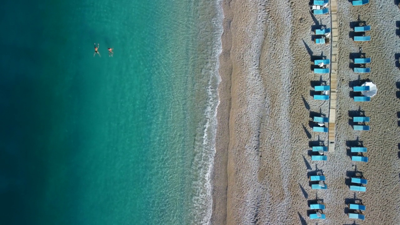 在土耳其的Oludeniz，两名孤独的游客在空荡荡的沙滩上游泳视频素材