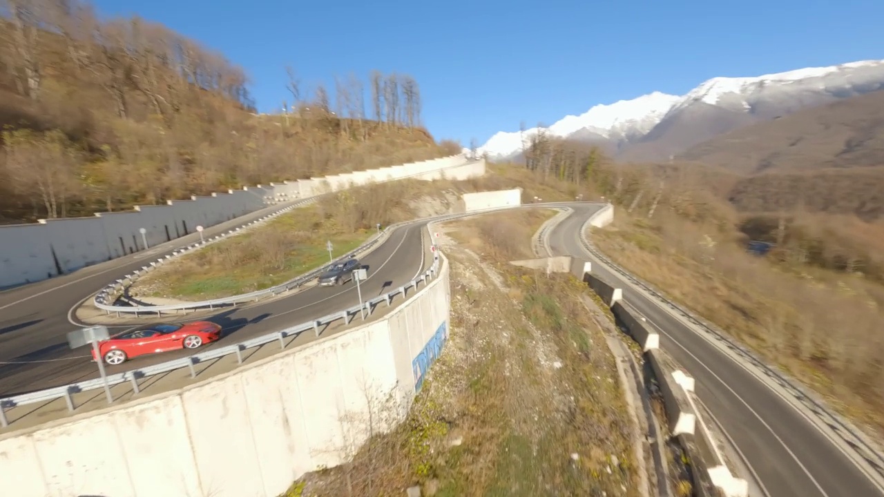 FPV无人机自由式拍摄红色跑车行驶在蜿蜒的沥青山路上视频下载