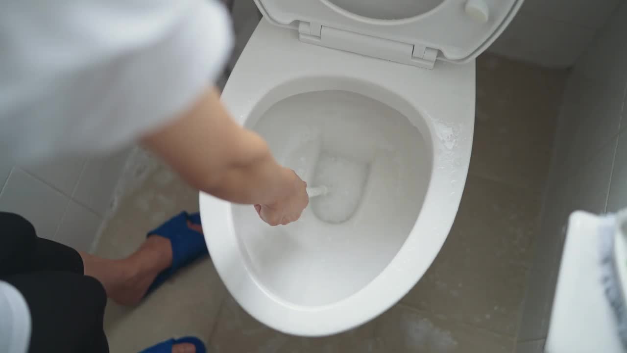 在浴室用马桶刷清洗完马桶后，用马桶刷冲水。家庭浴室，家庭生活视频素材