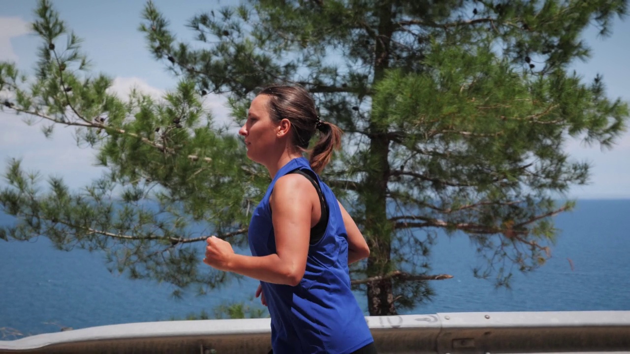 在户外跑步。精力充沛活跃的女性穿着运动服沿着海岸线跑步，做有氧健身运动。娱乐休闲活动。健身锻炼。在海滨慢跑的女性视频素材