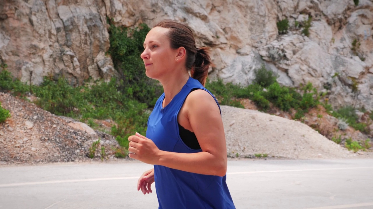 年轻积极的女人穿着运动服在山上跑步。活跃的女运动员在户外慢跑。健身锻炼锻炼。娱乐休闲活动。激烈的有氧运动。运动动机视频素材