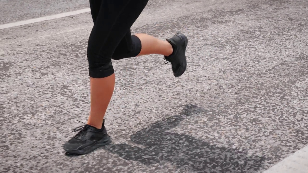 穿着运动鞋的女性脚在户外跑步。在空旷的道路上慢跑的健美女人的腿的特写。强度，耐力，跑步，锻炼，锻炼。健身的动机。体育的概念。娱乐活动视频素材