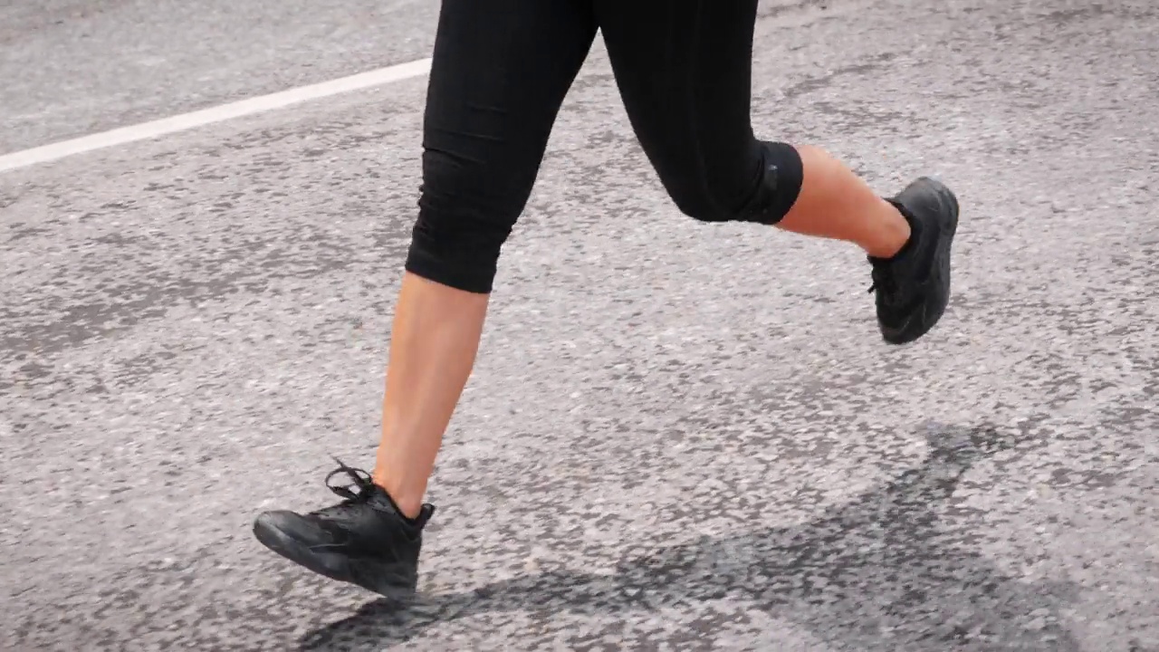 健美的女人在山路上慢跑。女性的双腿在灰色的柏油路上奔跑。跑马拉松。健身有氧运动。耐力锻炼锻炼。运动动机。休闲健身活动视频素材
