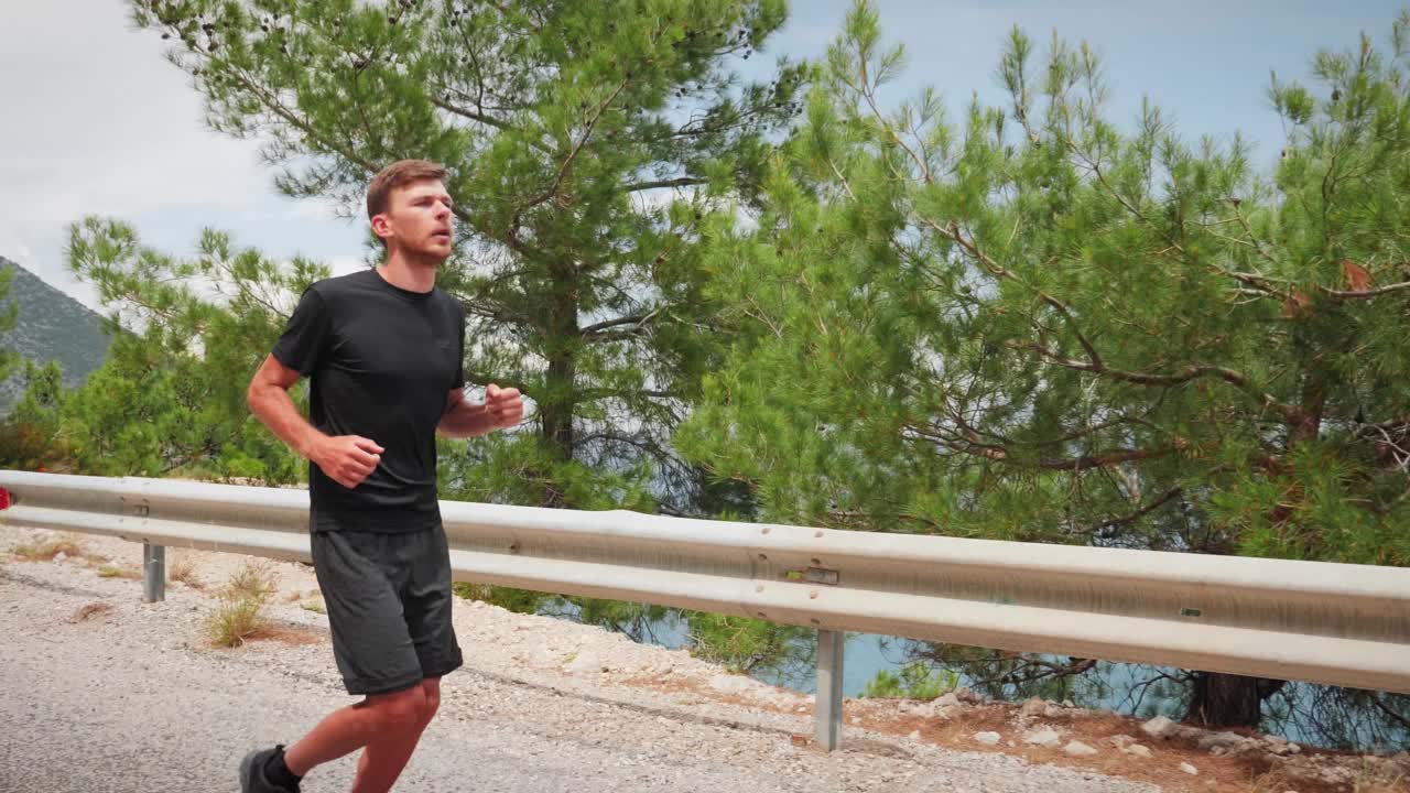 运动员沿着山道奔跑，背景是大海。跑步的人。男性跑步者在户外训练，在山路上锻炼。健美英俊的运动员慢跑者正在为马拉松赛跑做准备视频素材