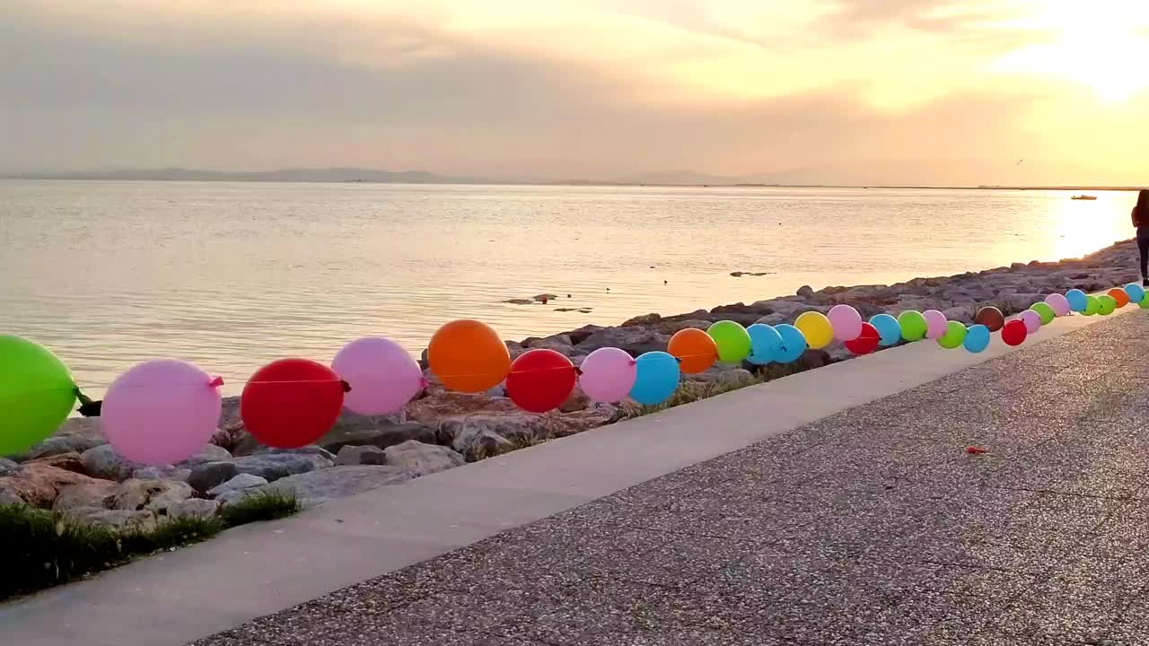 五颜六色的玩具气球排列在海滩上的绳子上视频下载