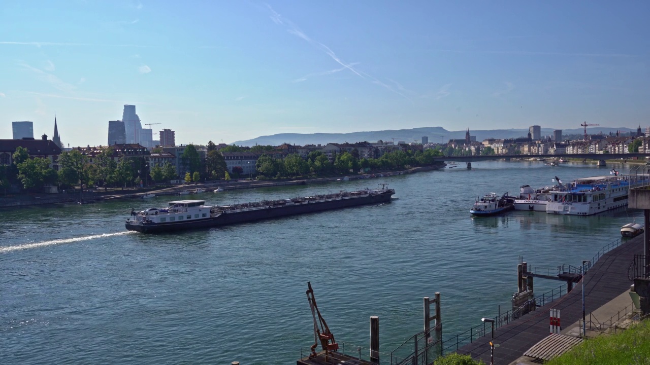 在一个阳光明媚的春天，一艘货船在巴塞尔市的莱茵河上行驶。视频素材