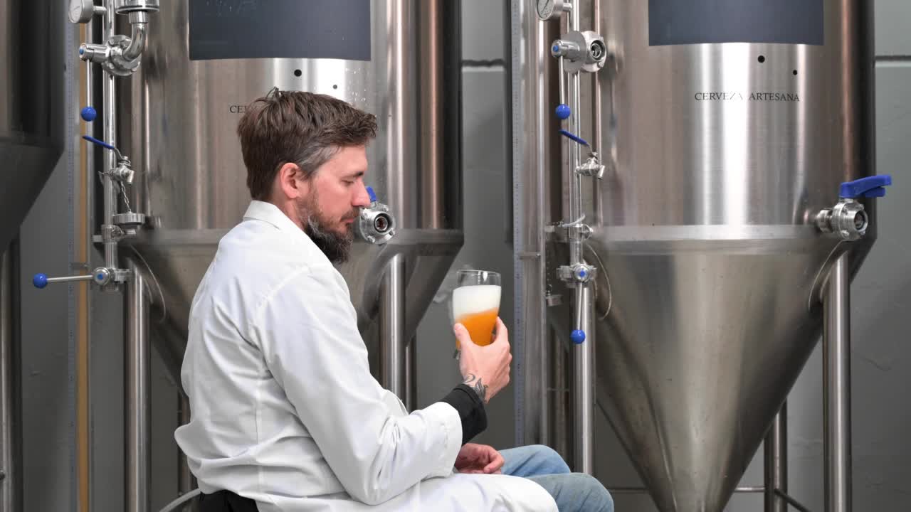 身着白大褂的酿酒工人在现代啤酒厂控制啤酒发酵过程。高质量4k镜头视频下载
