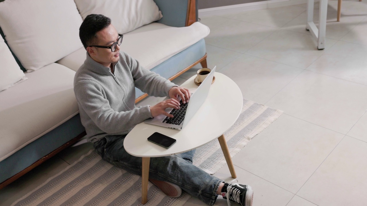 中年男子在家边喝咖啡边用笔记本电脑工作视频下载
