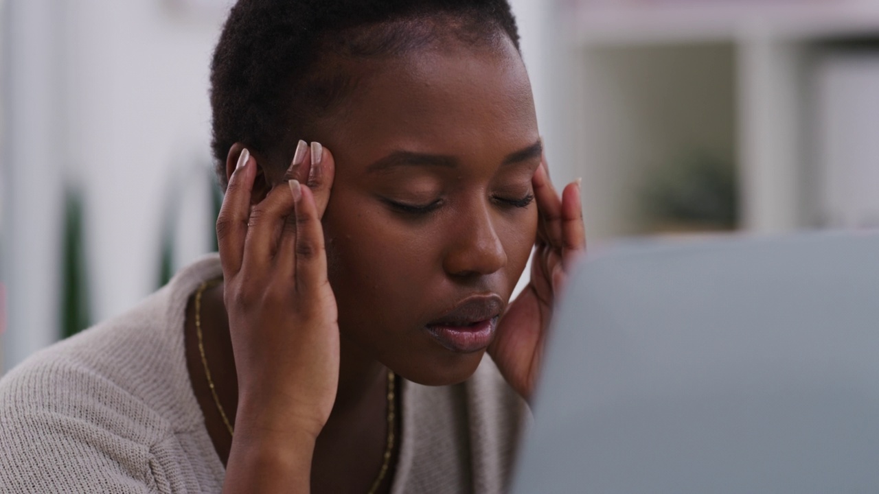 非洲裔美国女商人在办公室使用笔记本电脑时头痛。一位黑人女商人在工作时头痛。视频素材