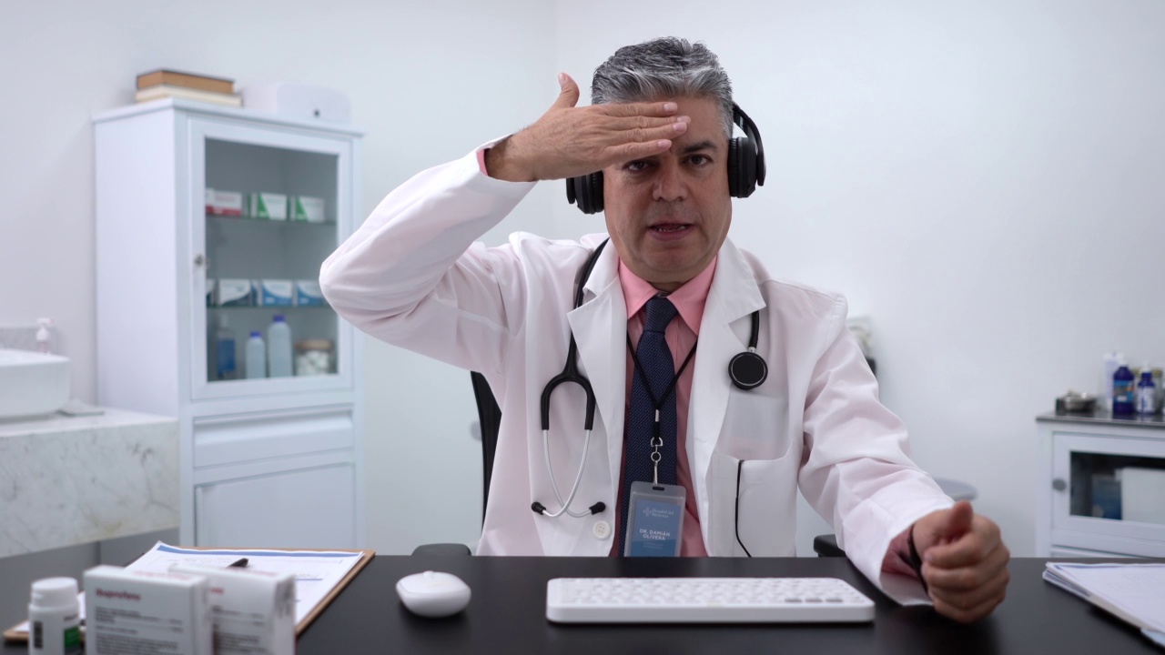 特写摄像头肖像细心的男医生在耳机与病人进行虚拟会议视频素材