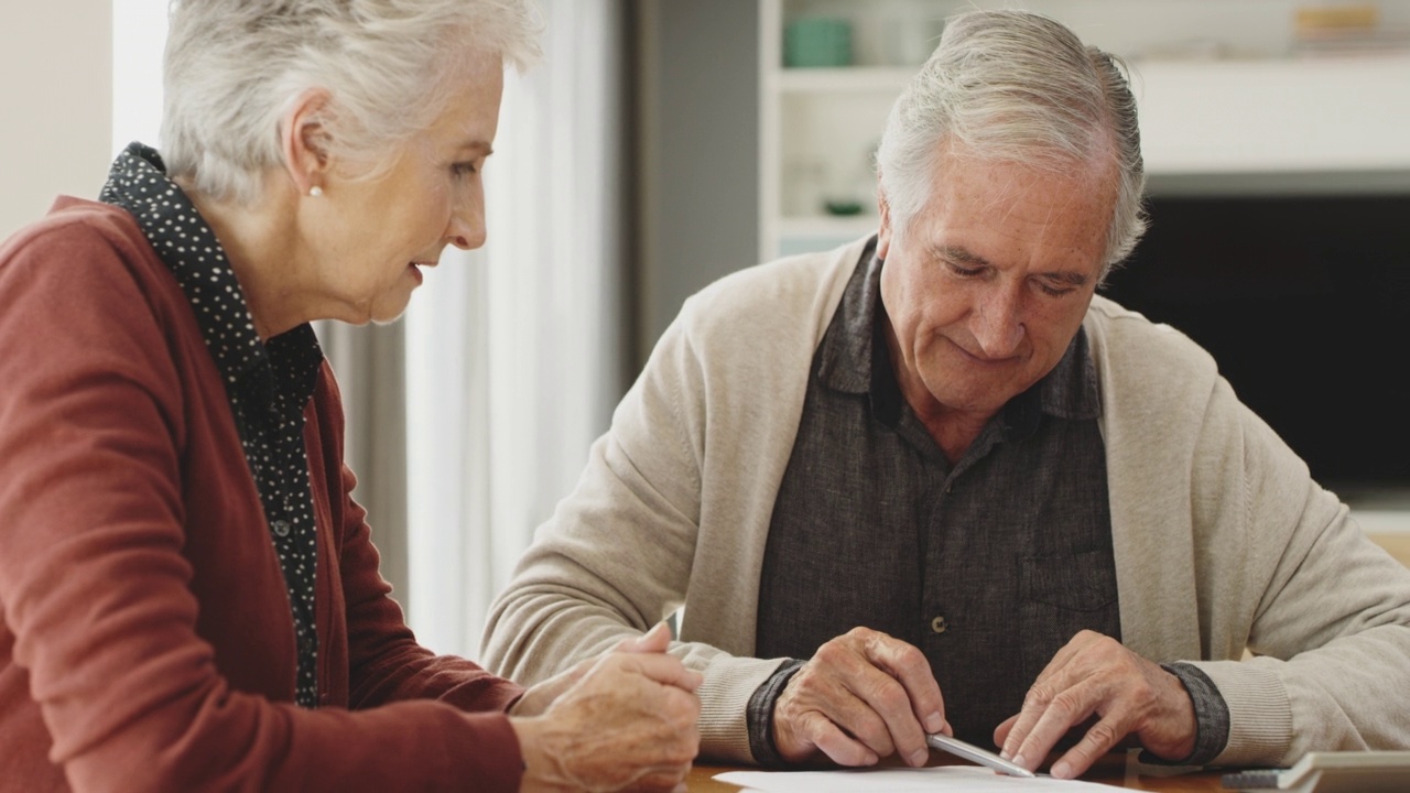 一对老年夫妇在家里一起处理文件。做财务预算的老年夫妇视频素材