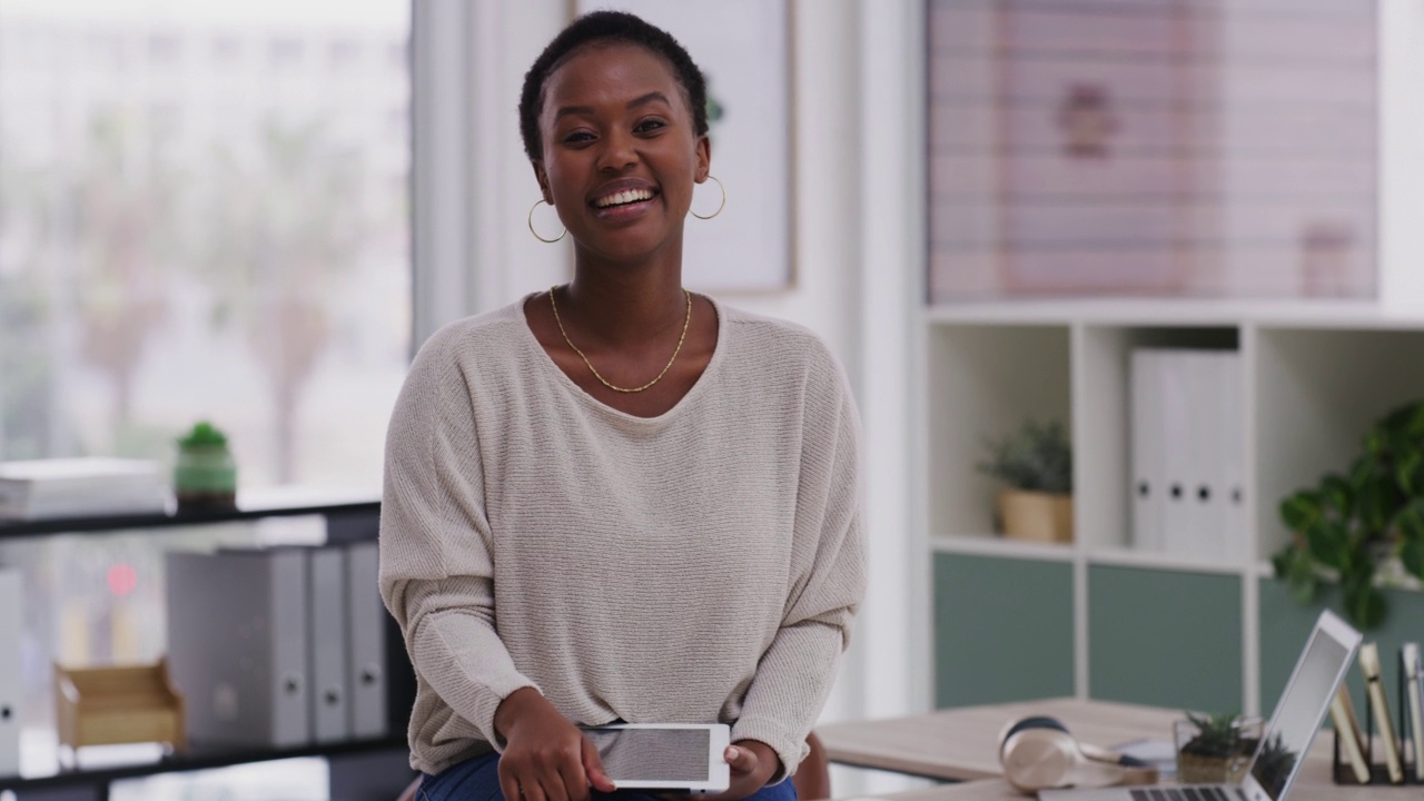 非洲裔美国女商人在现代办公室工作时手持数字平板电脑微笑。20多岁的年轻女商人站在办公室工作时，在休息时间使用电子平板电脑。视频素材