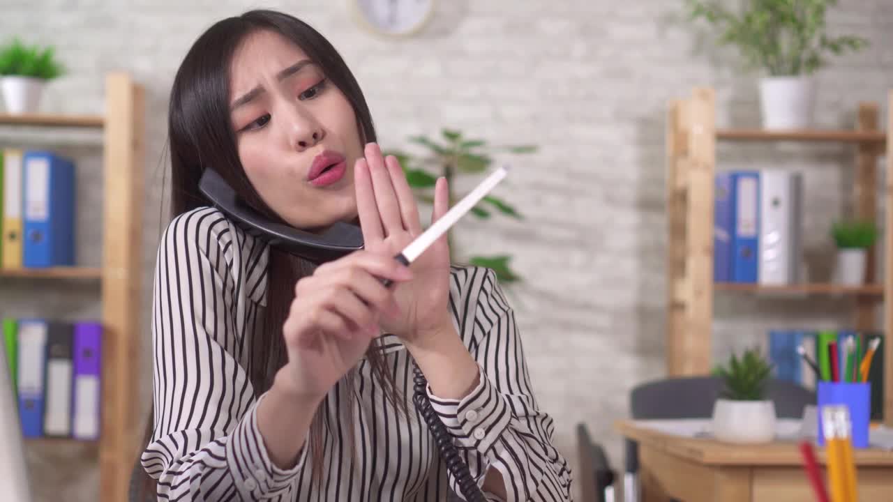 年轻的亚洲女性办公室职员在工作场所从事个人事务，在办公室里打电话聊天和锯钉子视频素材
