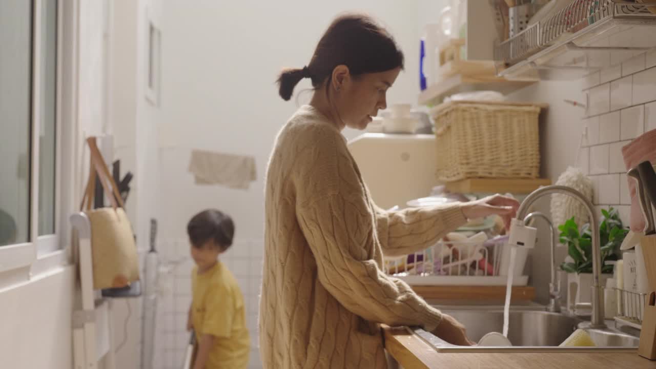 亚洲美女妈妈教小男孩打扫厨房。视频素材