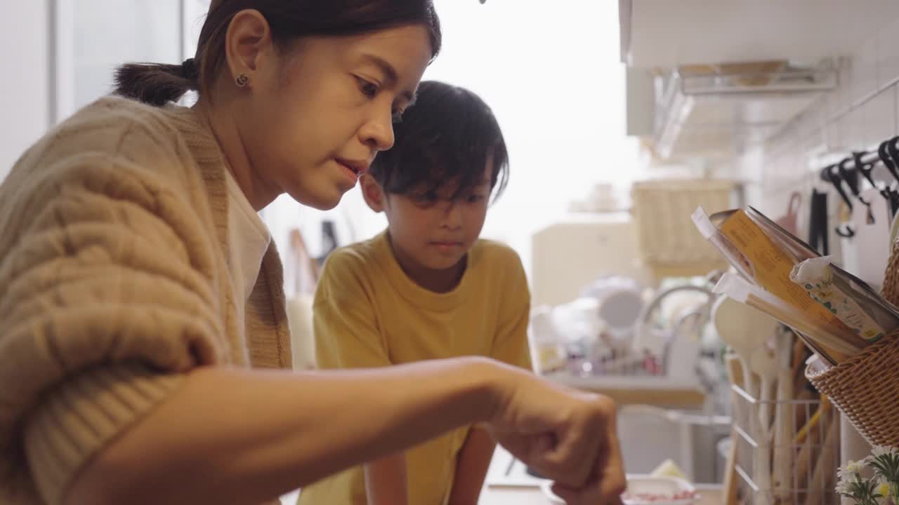 母亲和男孩在家厨房做饭视频素材