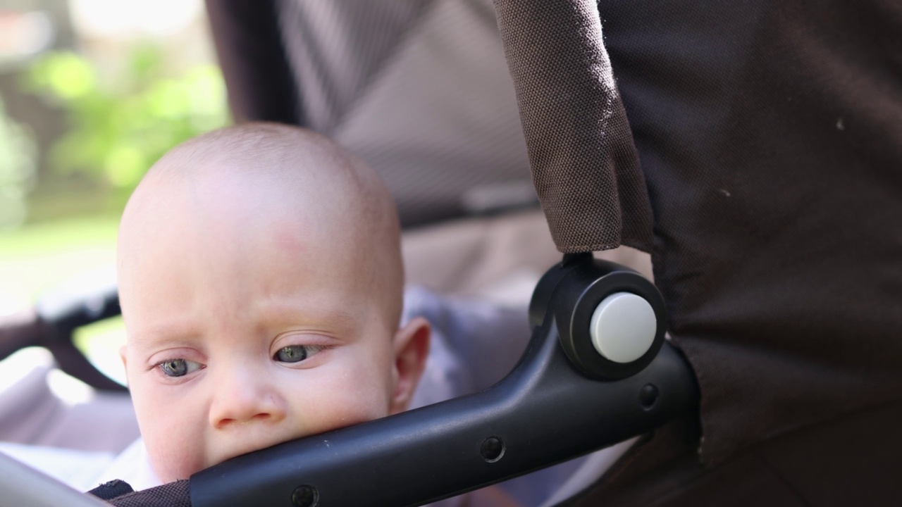 婴儿婴儿车婴儿肖像儿童脸，舔塑料部件的婴儿车视频素材