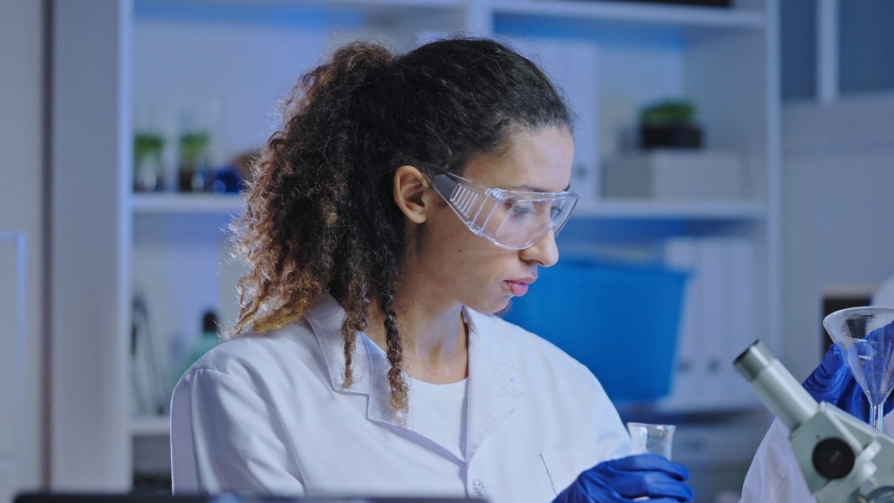 实验室女助理向液体中加入试剂，观察化学反应视频素材