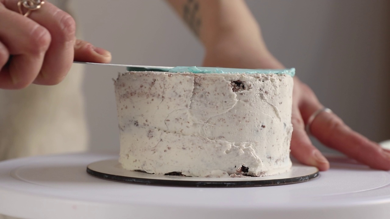 糖果师将蓝色奶油抹在圆形蛋糕上，用烹饪抹刀特写视频下载