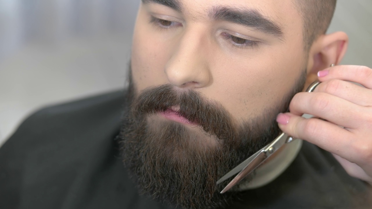 理发师用剪刀修剪胡子。视频素材