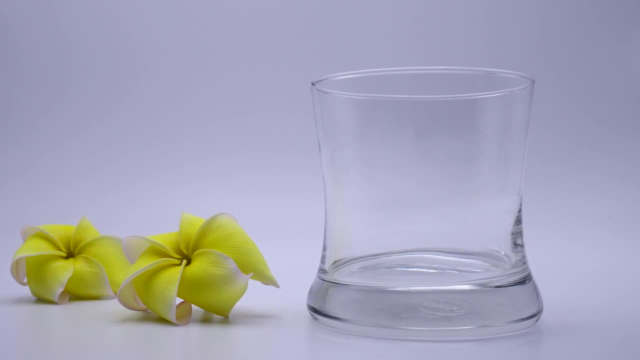 纯水倒进白色背景的玻璃杯。视频素材