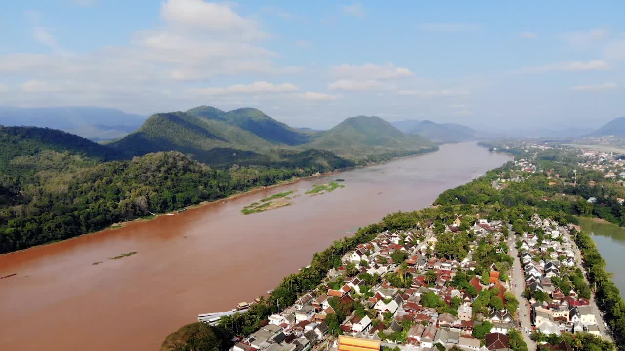鸟瞰老挝琅勃拉邦和周围郁郁葱葱的山脉。南汗河是湄公河的一条支流，在右边平静地流淌。视频素材