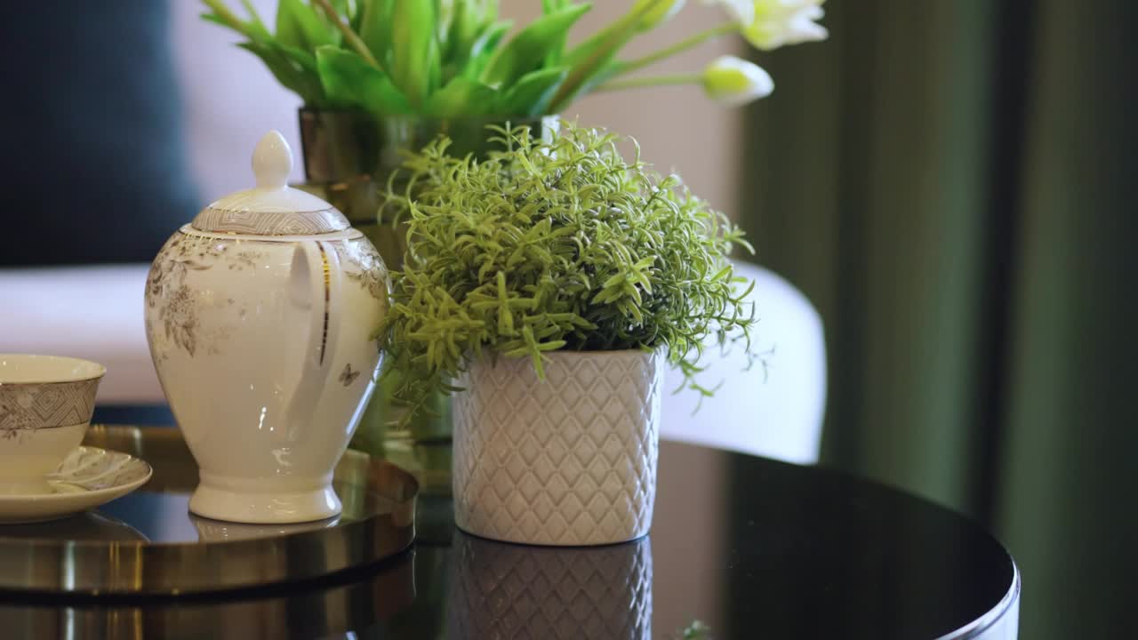 以白色窗帘为背景的餐厅餐桌上的白色陶土花瓶配以绿色装饰的新鲜树的室内设计理念视频下载