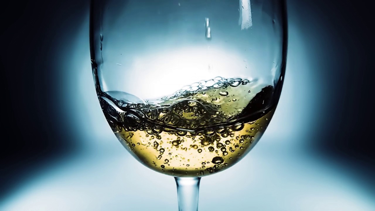 创意宏观慢动作4k视频白葡萄酒倒入玻璃杯。玻璃与倒白葡萄酒特写。用高速电影摄影机拍摄的。视频素材