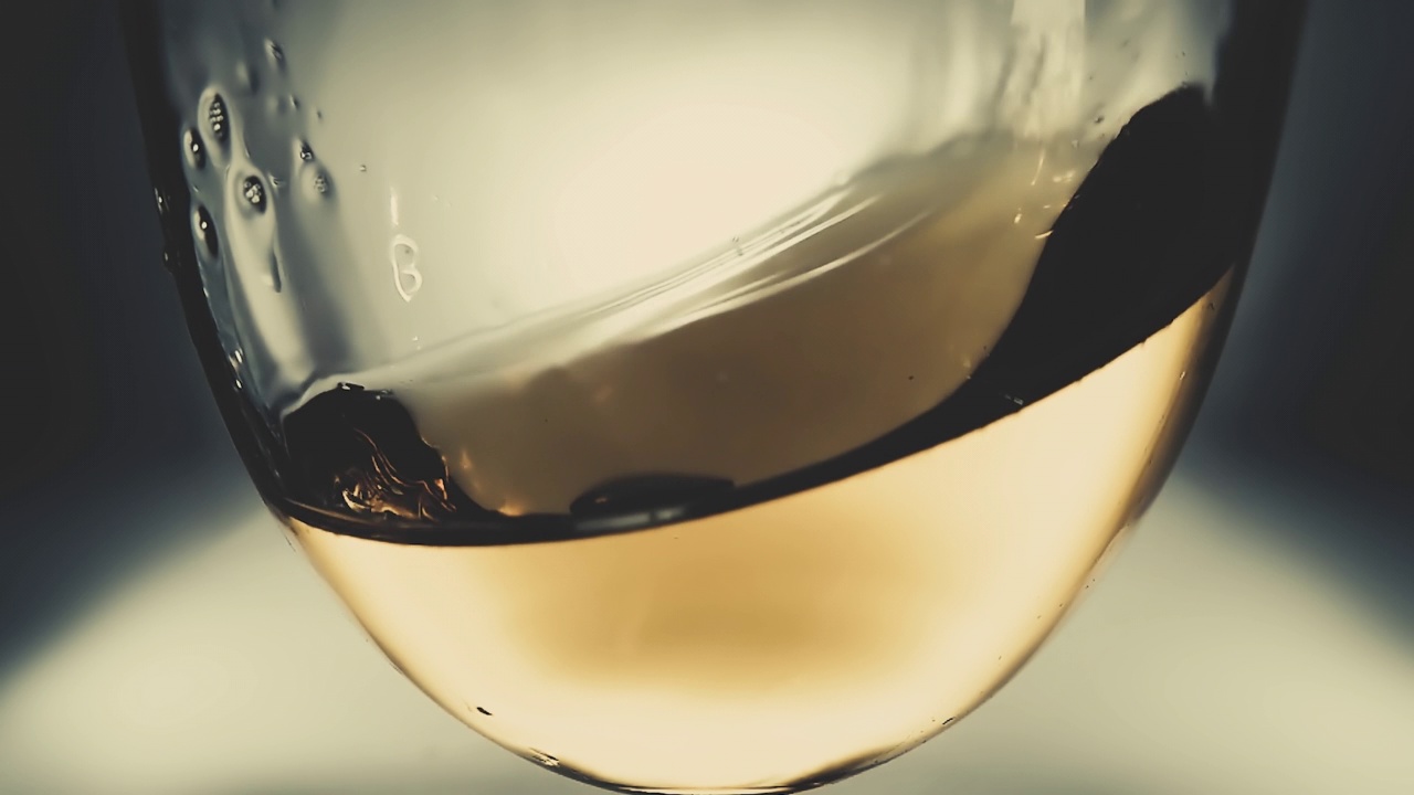 创意宏慢动作4k视频白葡萄酒溅在玻璃杯中。酒杯里晃酒的特写。用高速电影摄影机拍摄的。视频素材